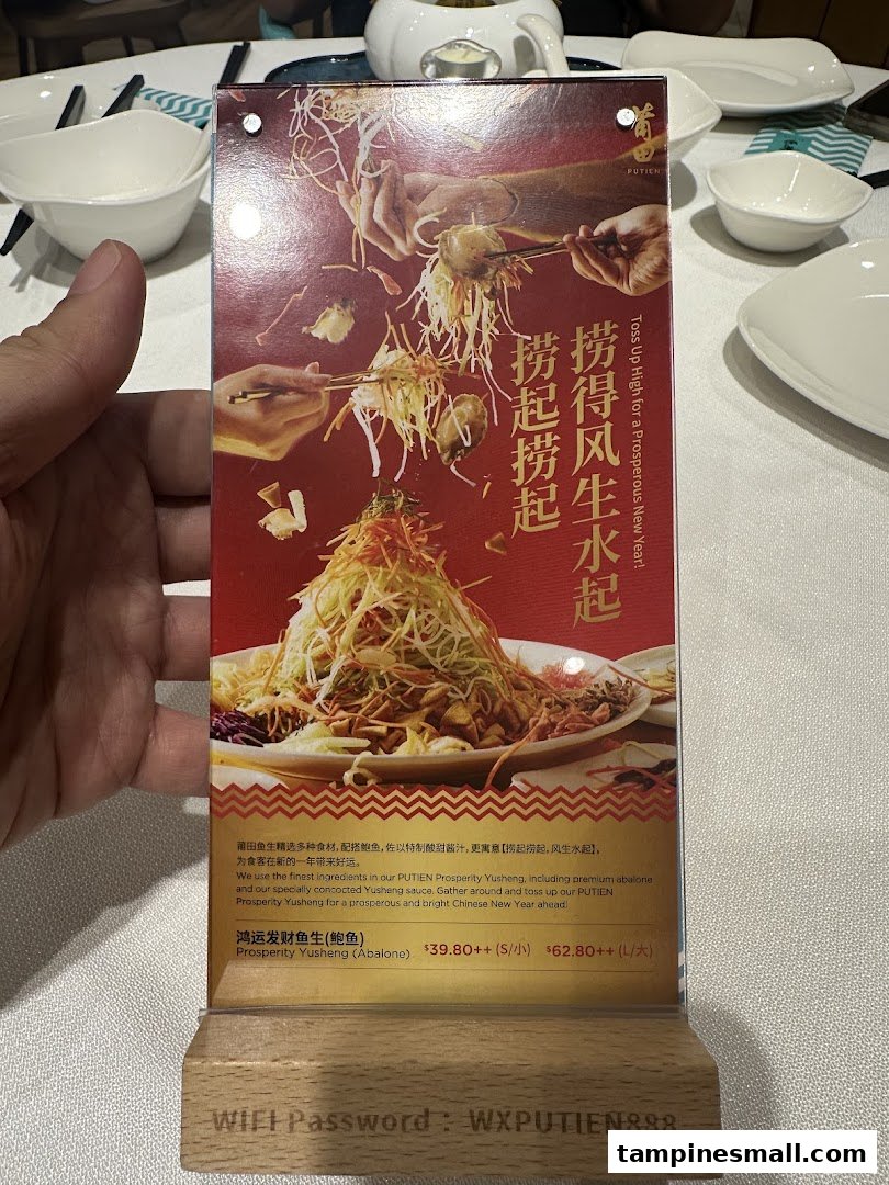 A promotional table tent displaying PUTIEN's Prosperity Yusheng dish with pricing and WiFi password.