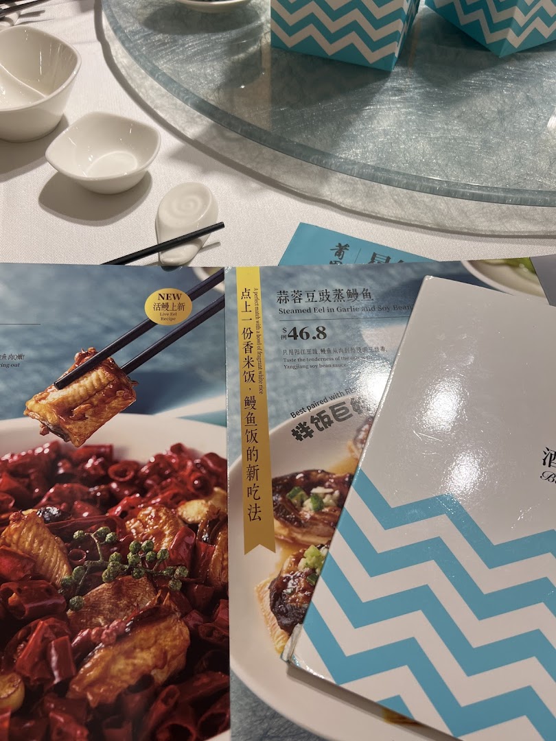 A close-up of PUTIEN's menu featuring Steamed Eel in Garlic and Soy Bean, alongside a table setting.