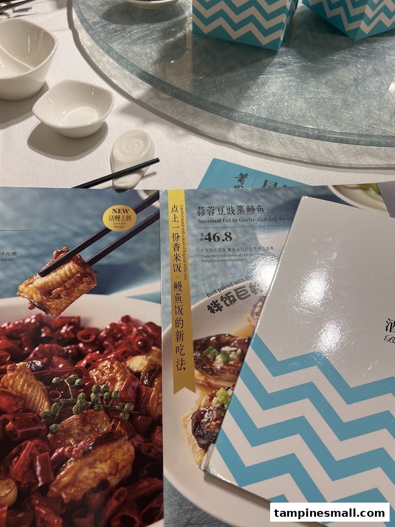 A close-up of PUTIEN's menu featuring Steamed Eel in Garlic and Soy Bean, alongside a table setting.