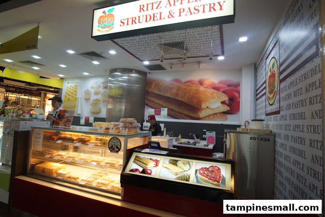 An interior view of Ritz Apple Strudel & Pastry, showcasing display cases filled with pastries and staff.