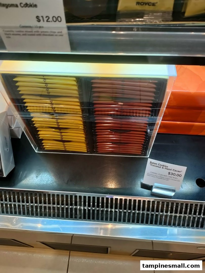 A display case showcasing Royce's Baton Cookies and other gourmet confections with price tags.