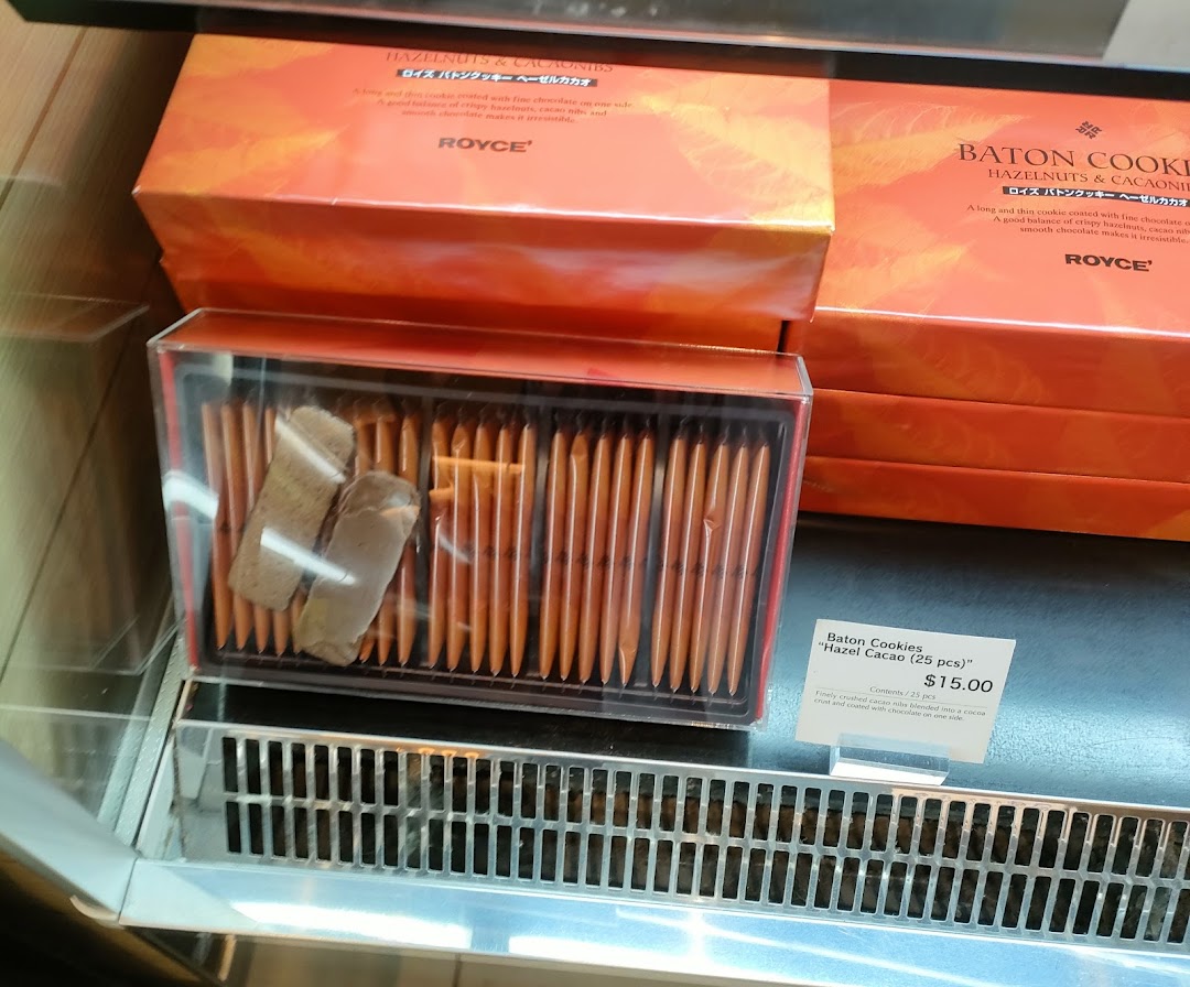 Royce's Hazel Cacao Baton Cookies are showcased in a display case with their distinctive packaging and price.