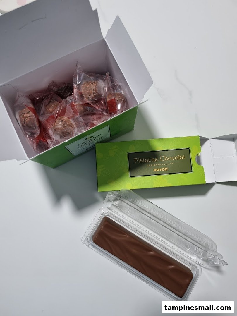 An open box of individually wrapped chocolates and a bar of Royce's Pistache Chocolat.