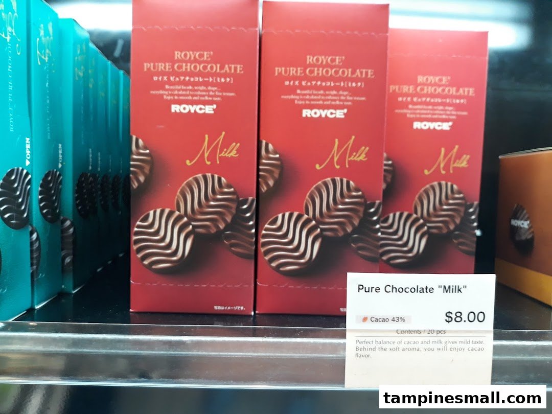 Boxes of Royce Pure Chocolate 'Milk' are displayed on a shelf with a price tag.