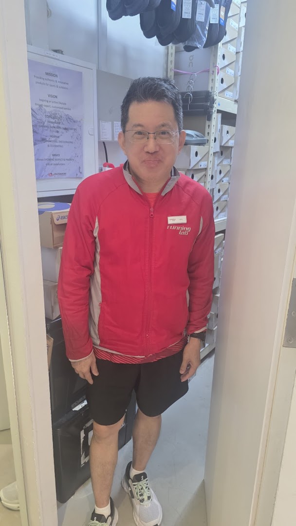 A staff member in a Running Lab jacket stands inside the store, surrounded by shoe boxes and merchandise.