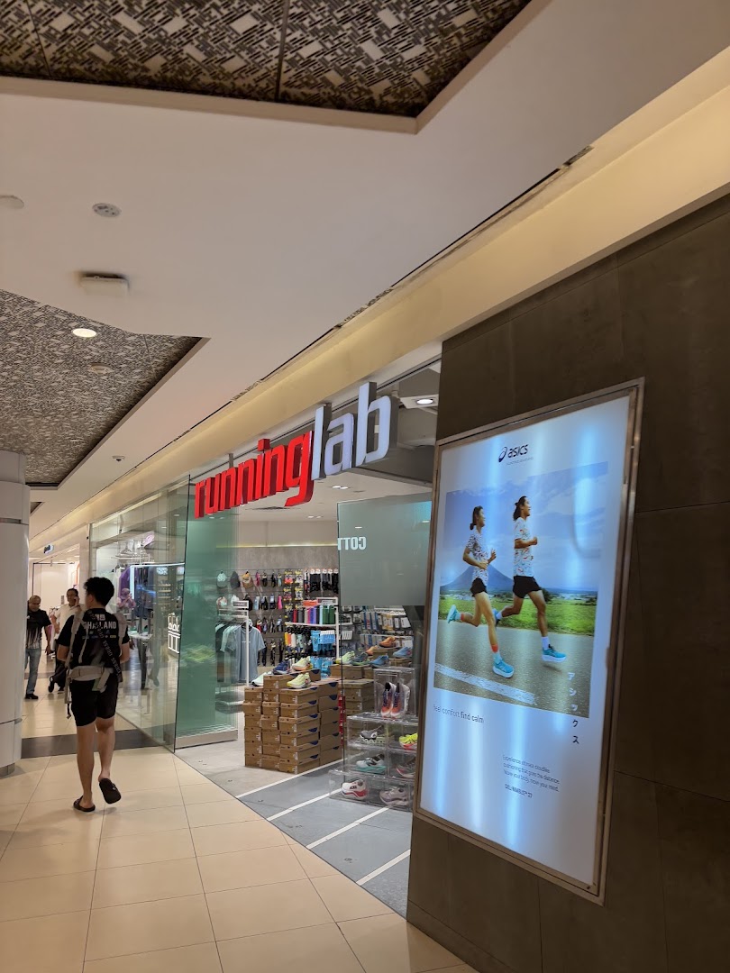 The storefront of Running Lab Tampines, showcasing athletic footwear and apparel, with an adjacent Asics advertisement.