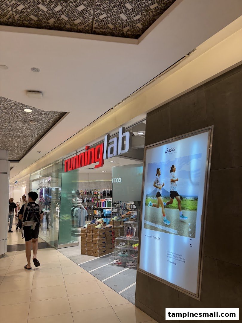 The storefront of Running Lab Tampines, showcasing athletic footwear and apparel, with an adjacent Asics advertisement.