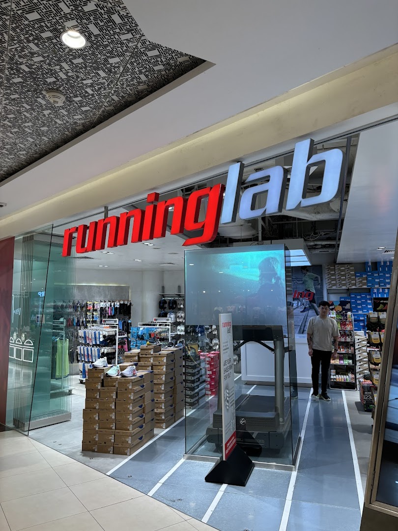 The storefront of Running Lab Tampines, showcasing its entrance, signage, and interior with shoes and a treadmill.