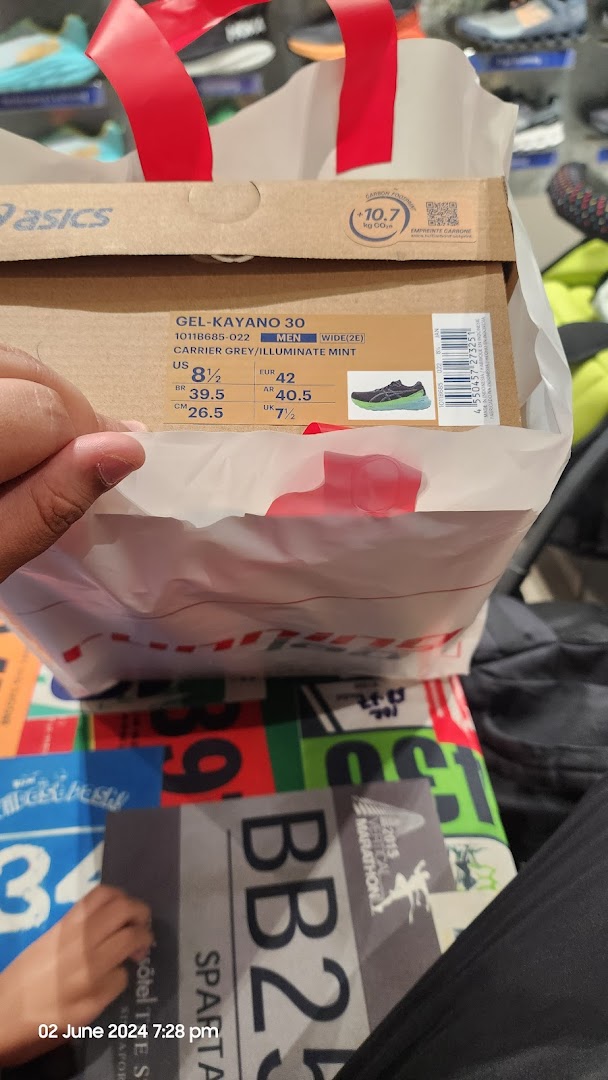 A customer holds a shopping bag with an Asics Gel-Kayano 30 shoe box inside Running Lab Tampines.