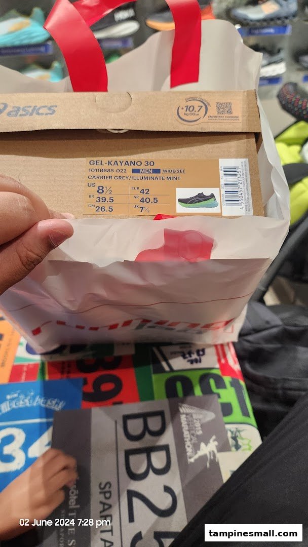 A customer holds a shopping bag with an Asics Gel-Kayano 30 shoe box inside Running Lab Tampines.