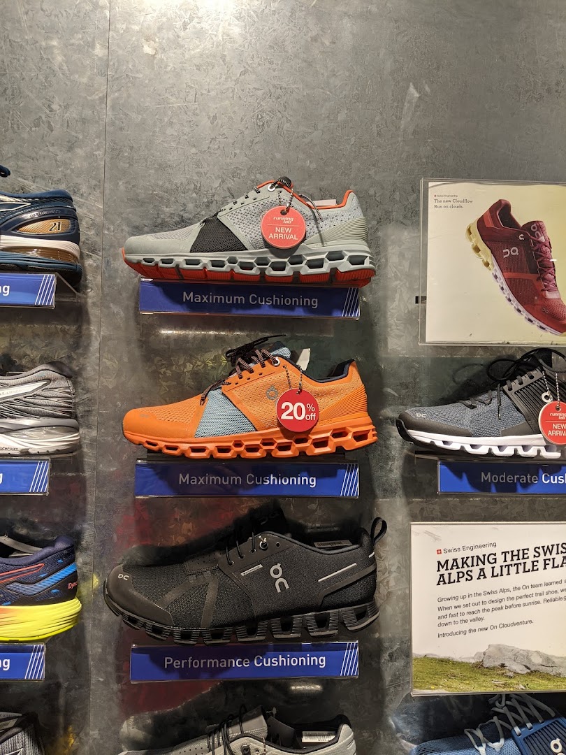 A wall display showcasing various running shoes with features like maximum cushioning and new arrivals.