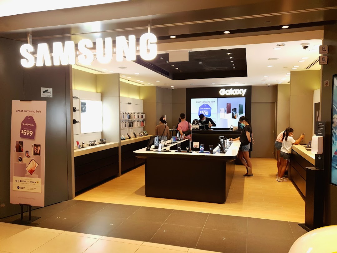 The entrance of a Samsung Experience Store with customers browsing various electronic devices and promotional displays.