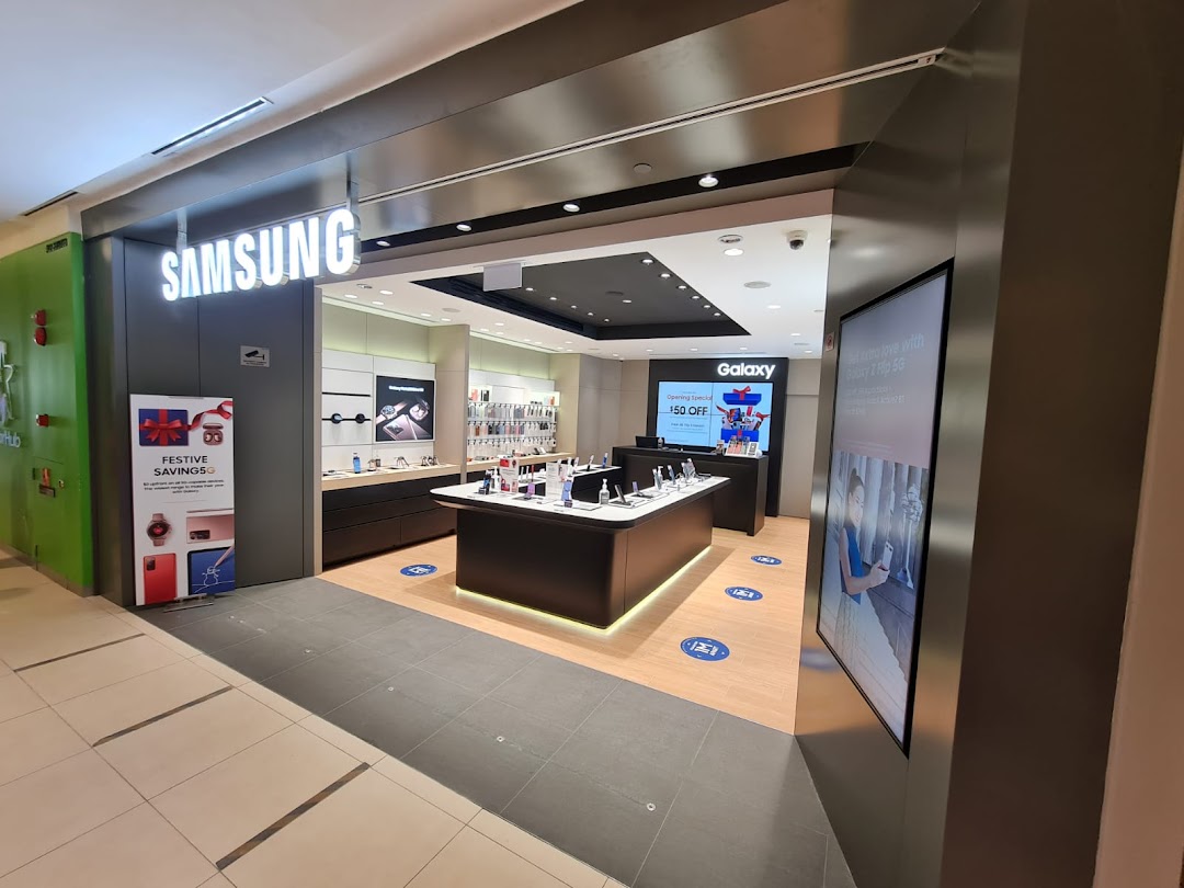 The brightly lit entrance of a Samsung Experience Store, showcasing display tables and promotional signage.