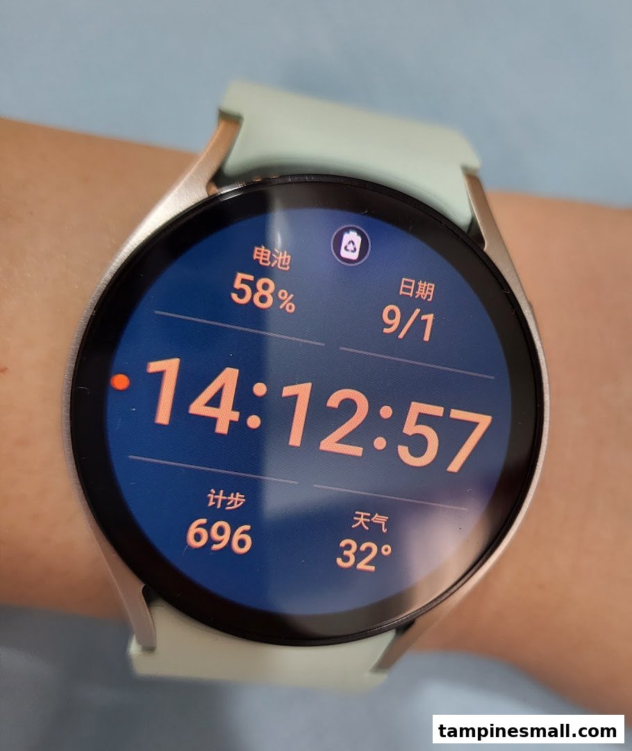 A close-up of a Samsung smartwatch on a wrist, displaying time, battery, date, steps, and weather.