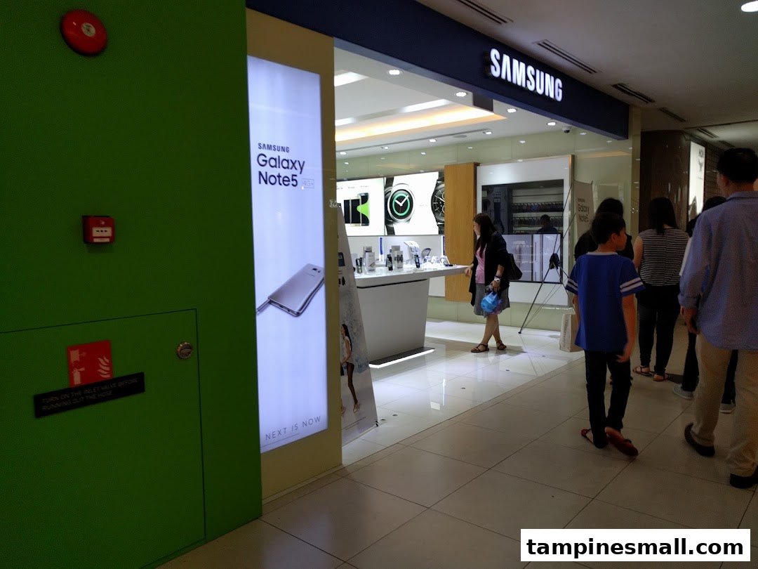 The brightly lit entrance of a Samsung Experience Store, showcasing products and inviting visitors inside.