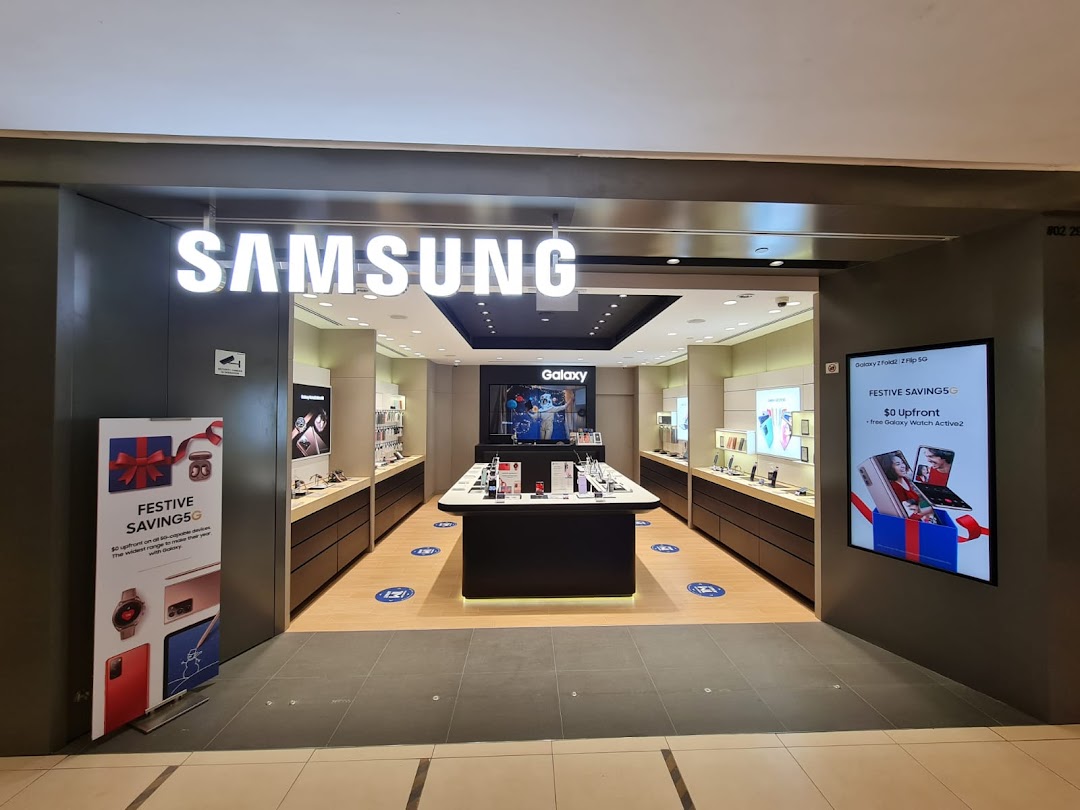 The brightly lit entrance of a Samsung Experience Store, showcasing various electronic products and promotional displays.