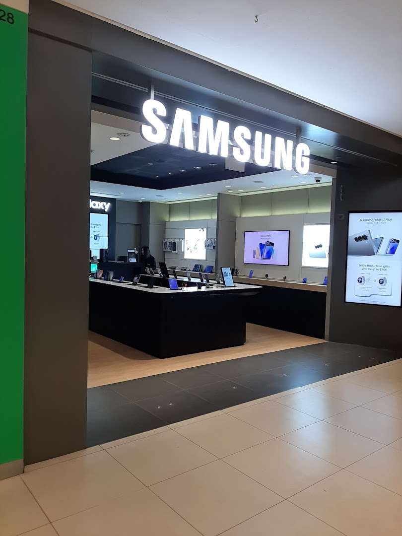 The image captures the inviting entrance of a Samsung Experience Store, showcasing its illuminated logo and modern interior displays.