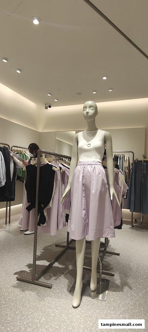 An interior view of SANS SANS clothing store, featuring a mannequin dressed in a white top and lavender skirt.