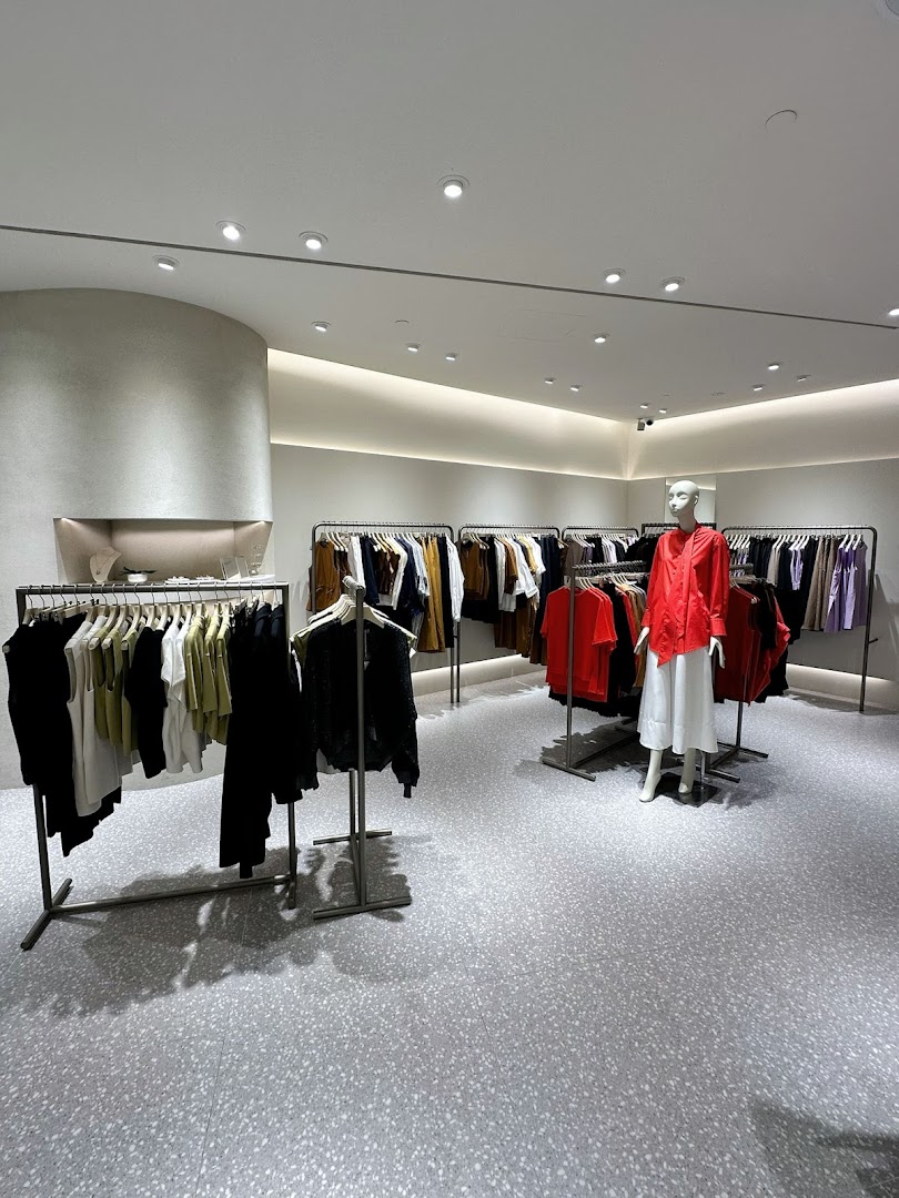 An interior view of SANS SANS clothing store, featuring modern racks of apparel and a mannequin.