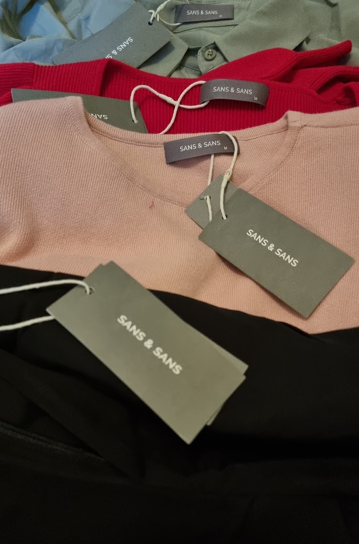 Close-up of various colored clothing items with 'SANS & SANS' brand tags.