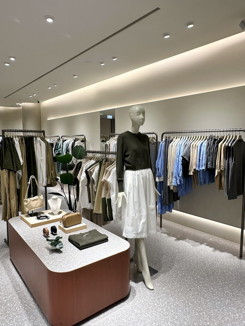 An interior view of SANS SANS Tampines Mall, showcasing clothing racks, a mannequin, and a display table.