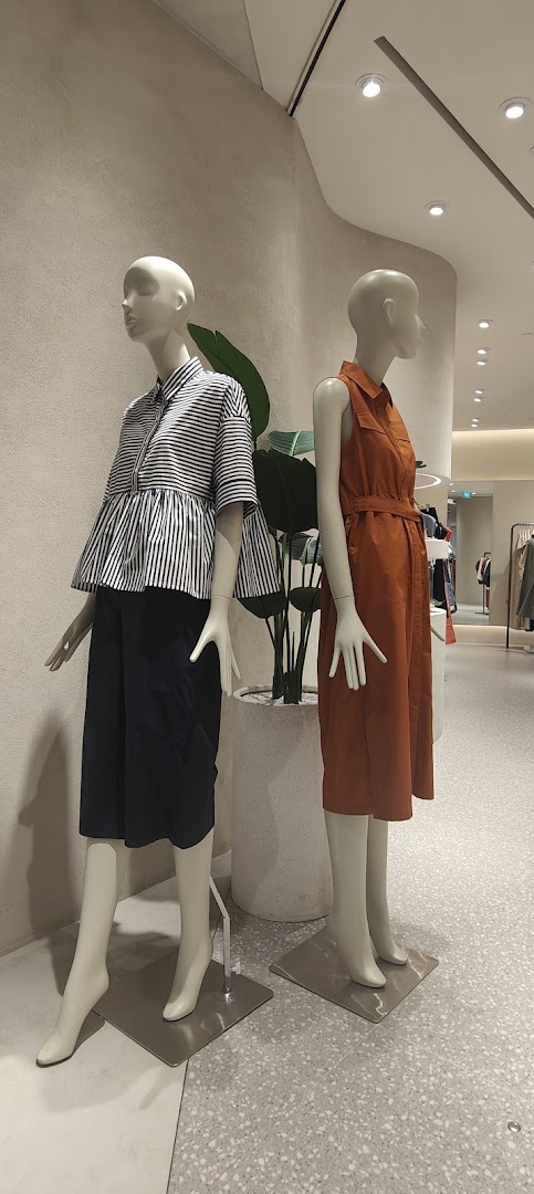 Two mannequins display stylish women's clothing inside a modern retail store.