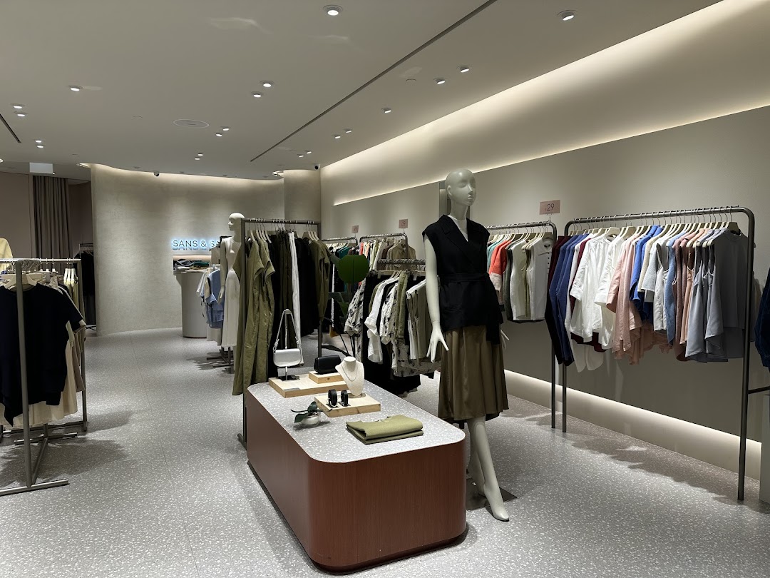 An interior view of SANS SANS, showcasing stylish clothing on racks and mannequins in a modern setting.