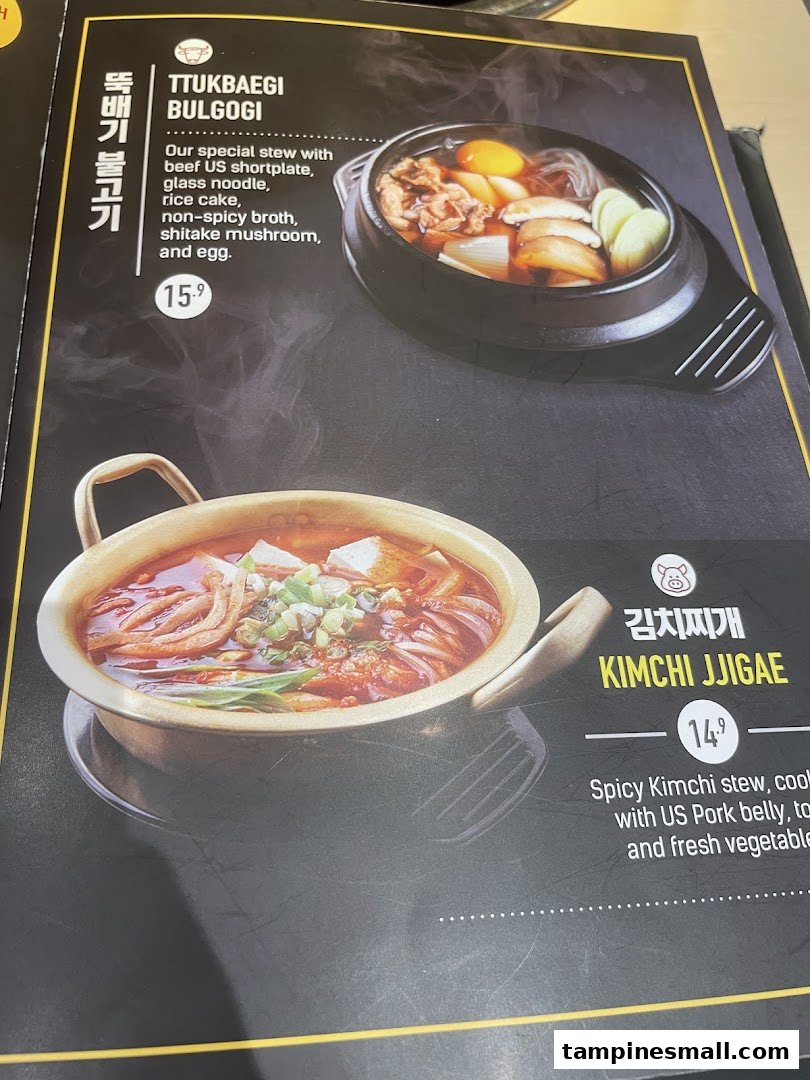 A close-up of a Korean restaurant menu featuring Ttukbaegi Bulgogi and Kimchi Jjigae.