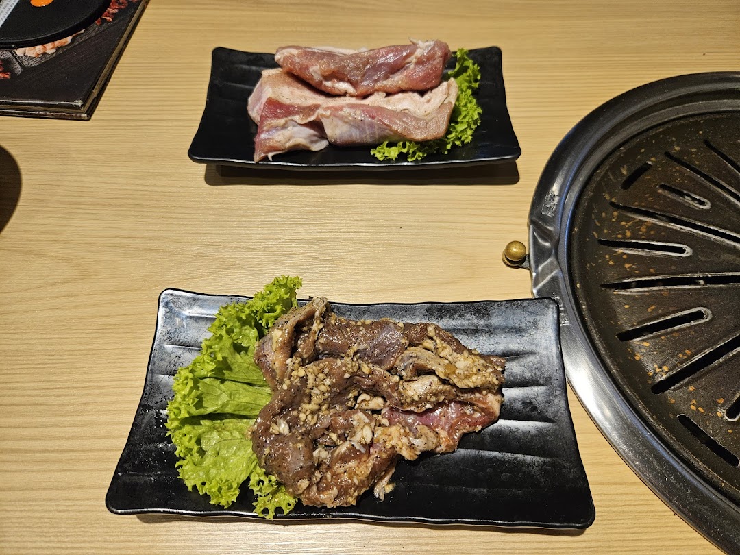 Two plates of raw meat, one marinated, ready for grilling at Seorae Jib.
