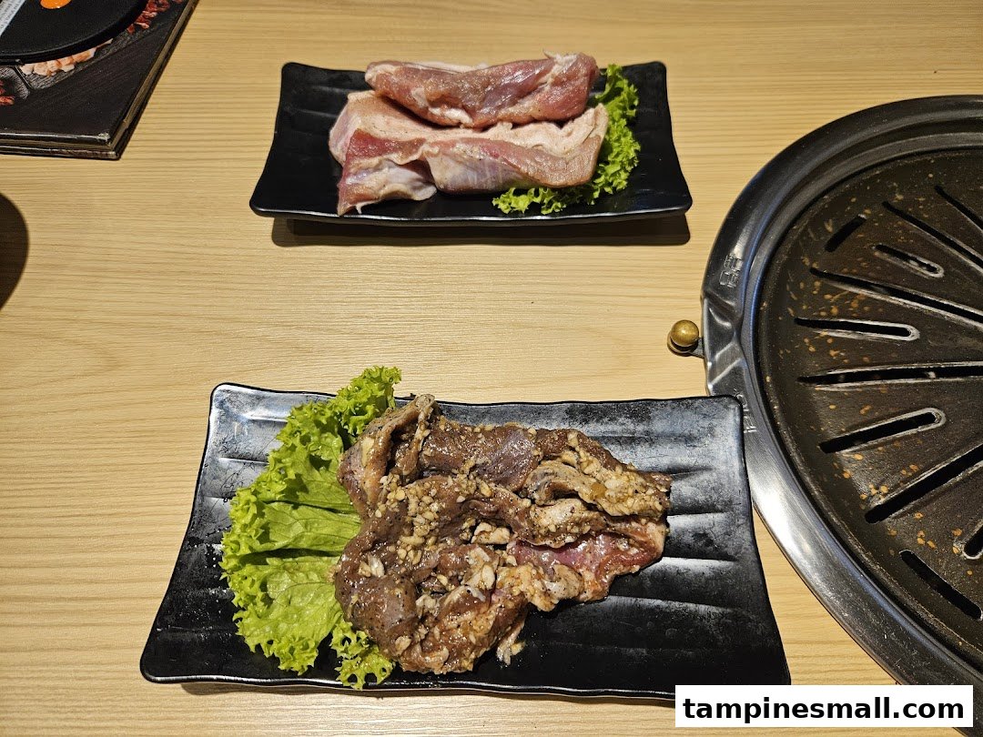 Two plates of raw meat, one marinated, ready for grilling at Seorae Jib.