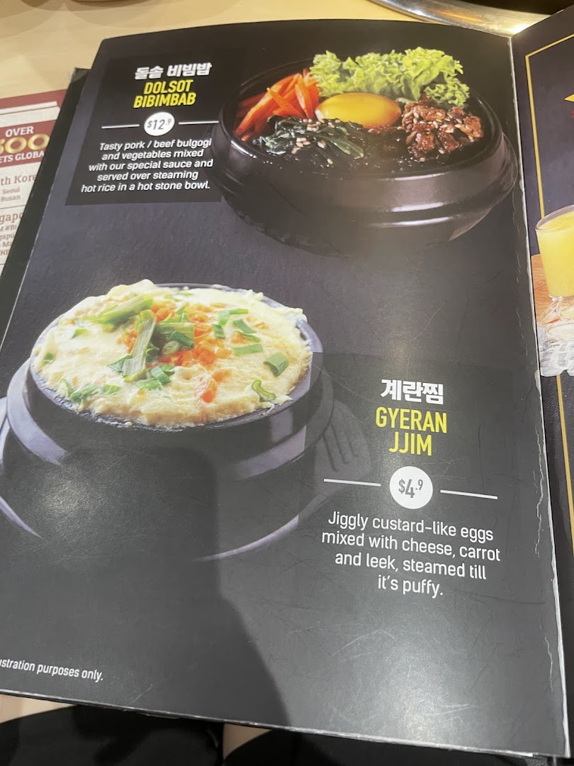 A close-up of a menu page featuring Dolsot Bibimbab and Gyeran Jjim with descriptions and prices.
