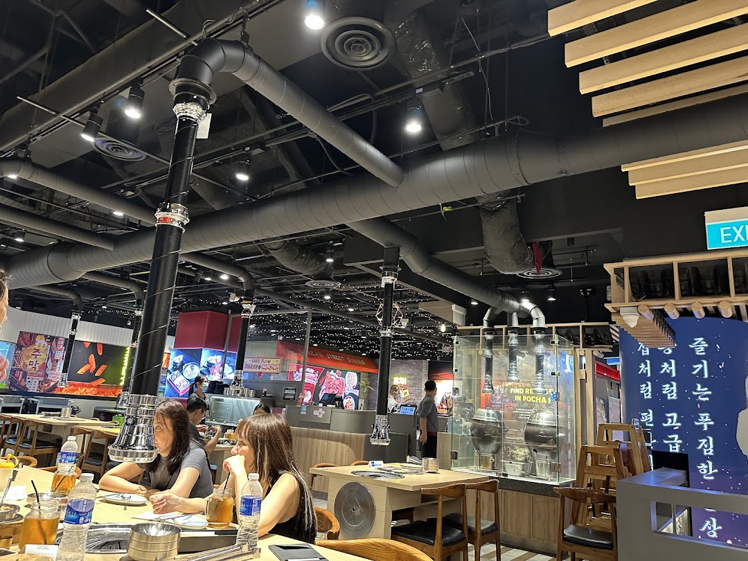 Interior view of a bustling Korean BBQ restaurant with diners and industrial-style decor.