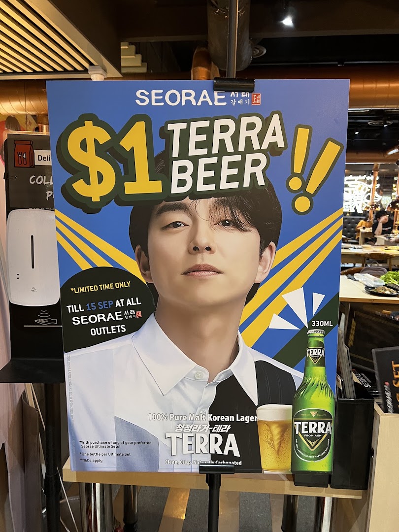 A promotional standee for $1 Terra Beer at Seorae Jib, featuring a celebrity and offer details.
