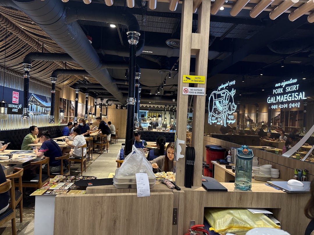 A bustling interior view of Seorae Jib, a Korean BBQ restaurant, with diners enjoying their meals.