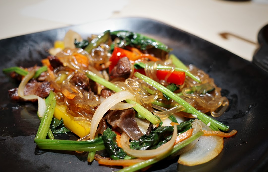 A vibrant plate of Korean Japchae with glass noodles, colorful vegetables, and savory meat.