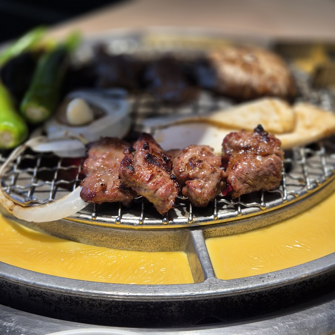 Close-up of grilled meat and vegetables sizzling on a Korean BBQ grill.