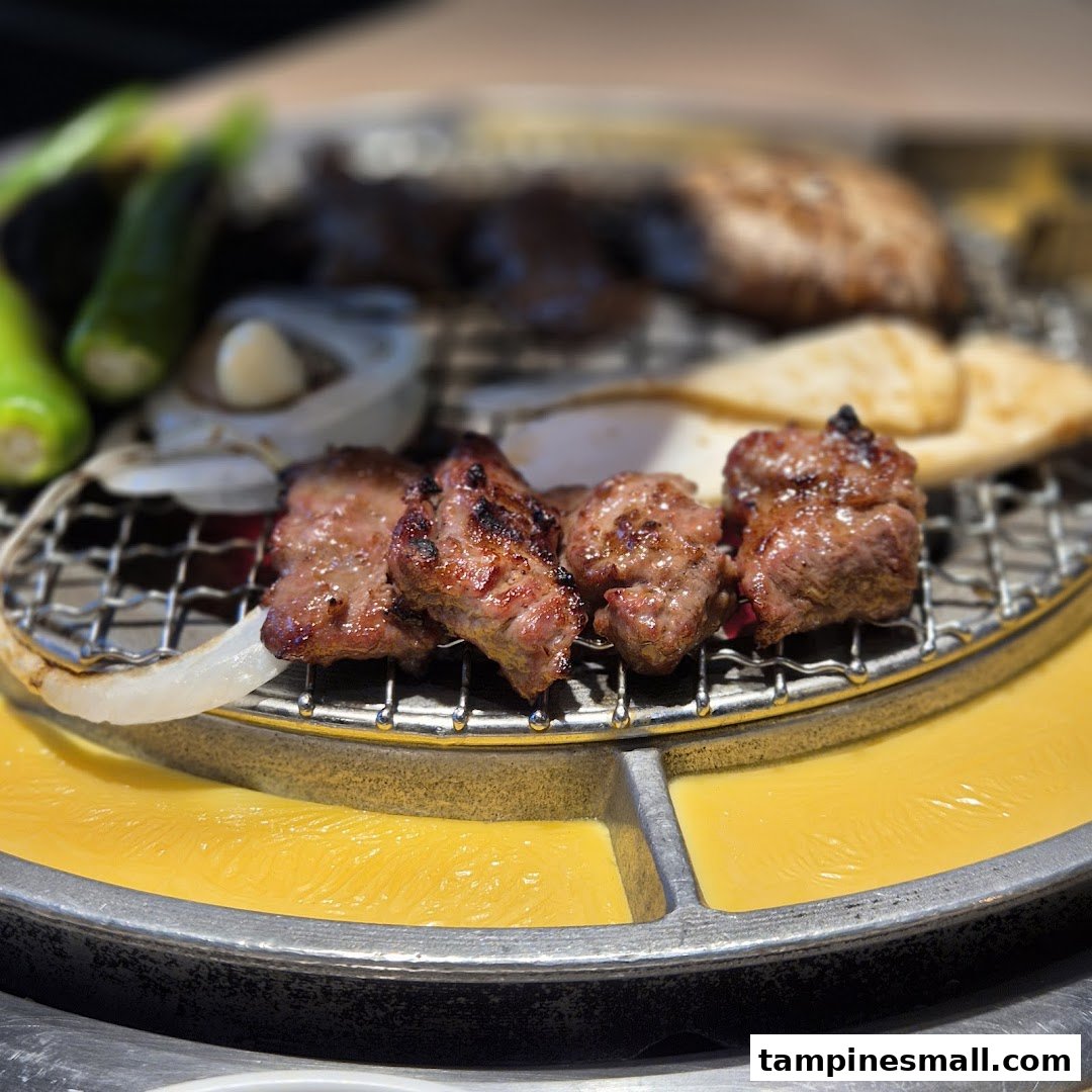 Close-up of grilled meat and vegetables sizzling on a Korean BBQ grill.