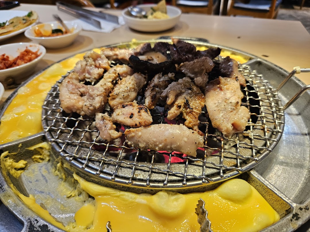Delicious Korean BBQ grilling on a tabletop with melted cheese and various side dishes.