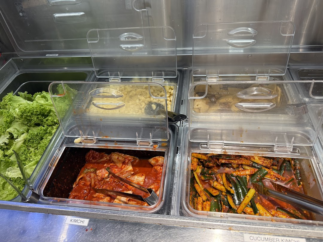 A vibrant display of fresh Korean banchan, including kimchi and cucumber kimchi, ready for self-service.