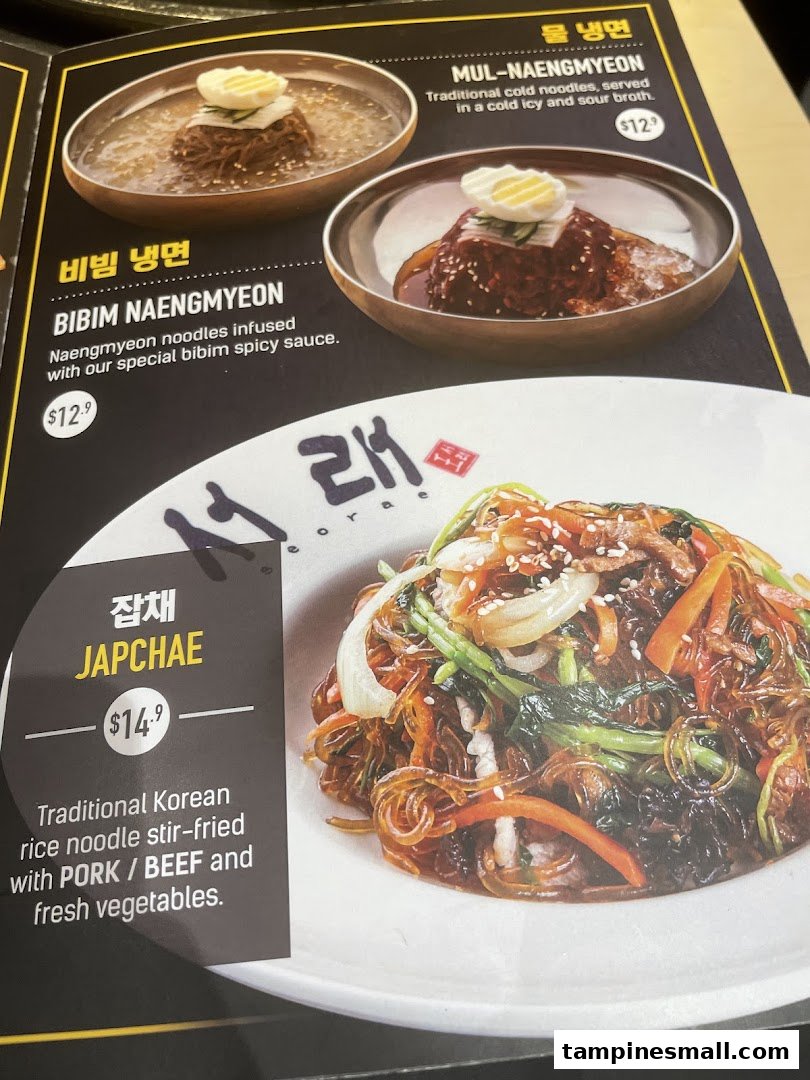 A close-up image of a menu displaying various Korean noodle and stir-fried dishes with prices.