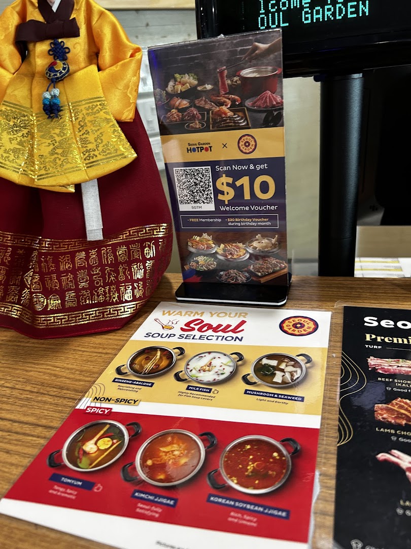 A table display featuring Seoul Garden's soup menu, hotpot promotions, and a traditional Korean doll.