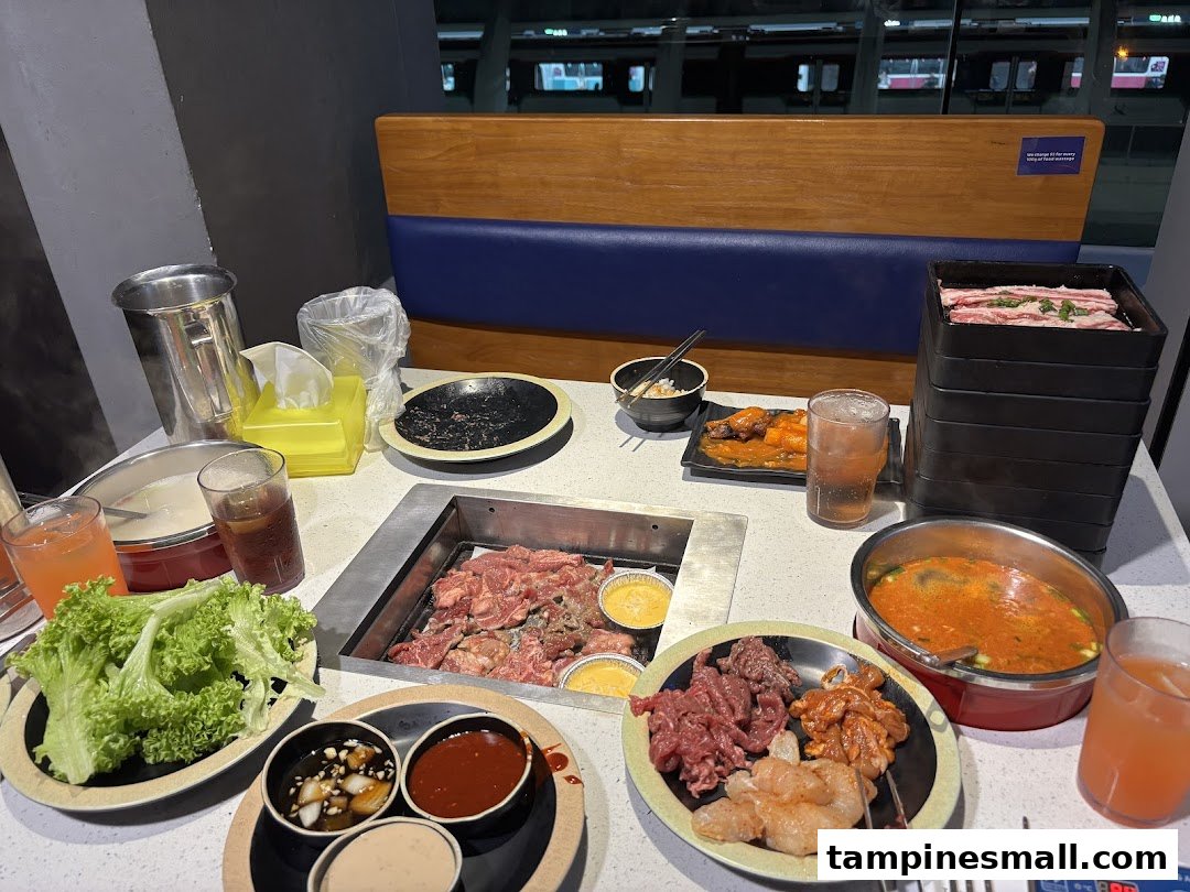 A dining table at Seoul Garden with a grill, raw meats, soup, and various Korean BBQ dishes.