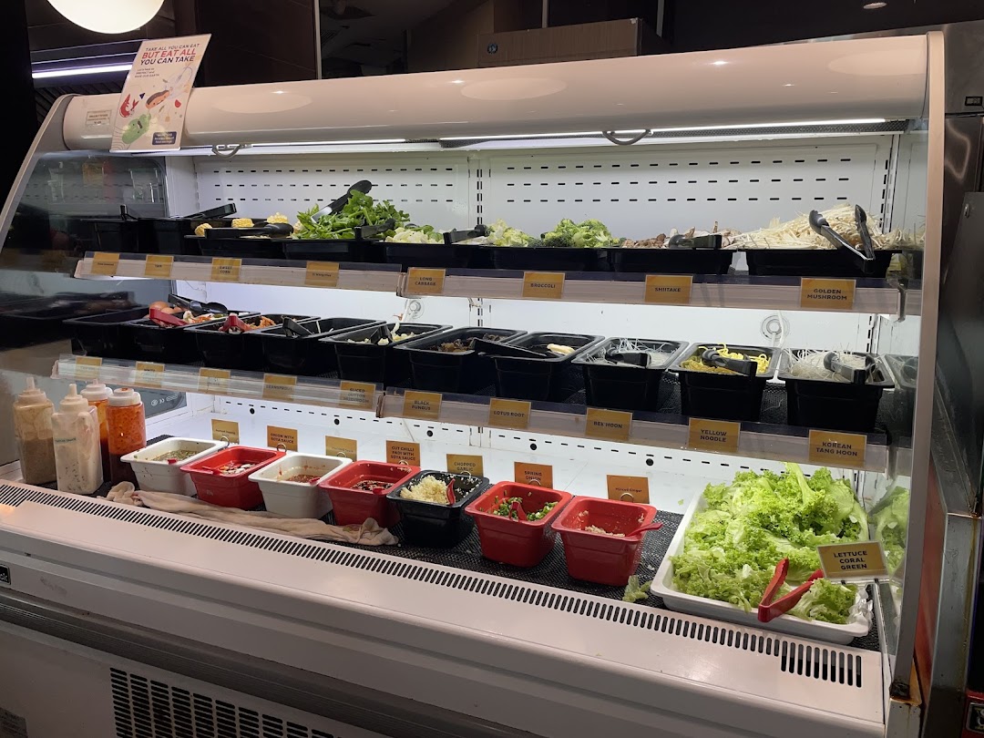 A refrigerated display case showcasing a wide variety of fresh ingredients and condiments for a buffet.