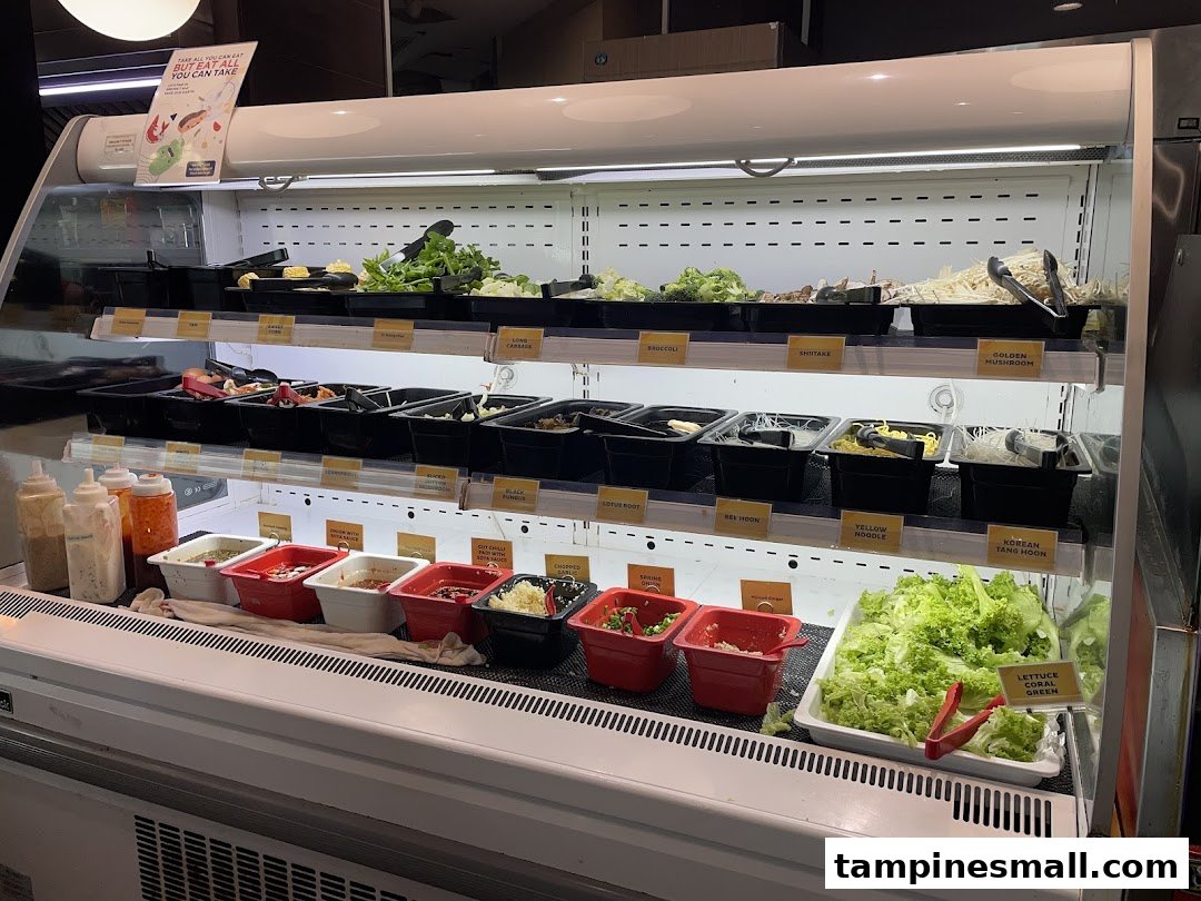 A refrigerated display case showcasing a wide variety of fresh ingredients and condiments for a buffet.