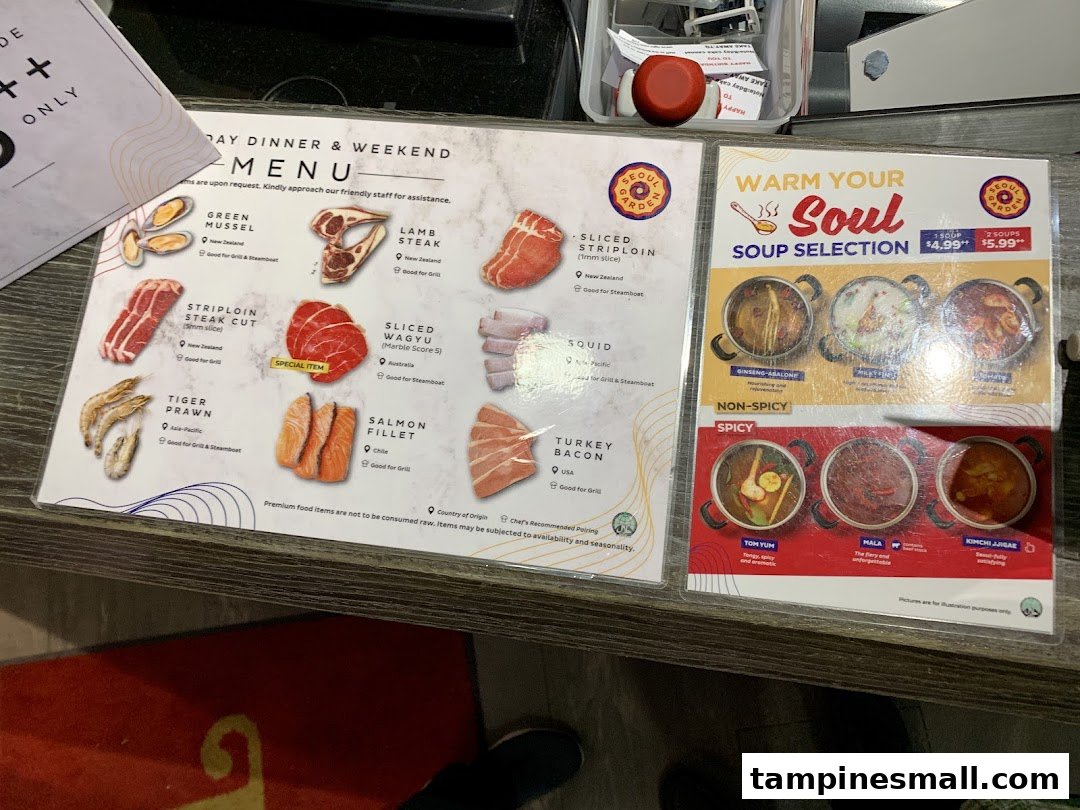 Two menus displayed on a counter, featuring BBQ/steamboat ingredients and soup selections.
