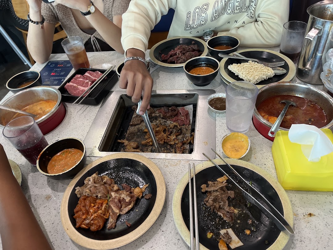 Diners enjoying a Korean BBQ and hotpot buffet with various meats and sauces at Seoul Garden.