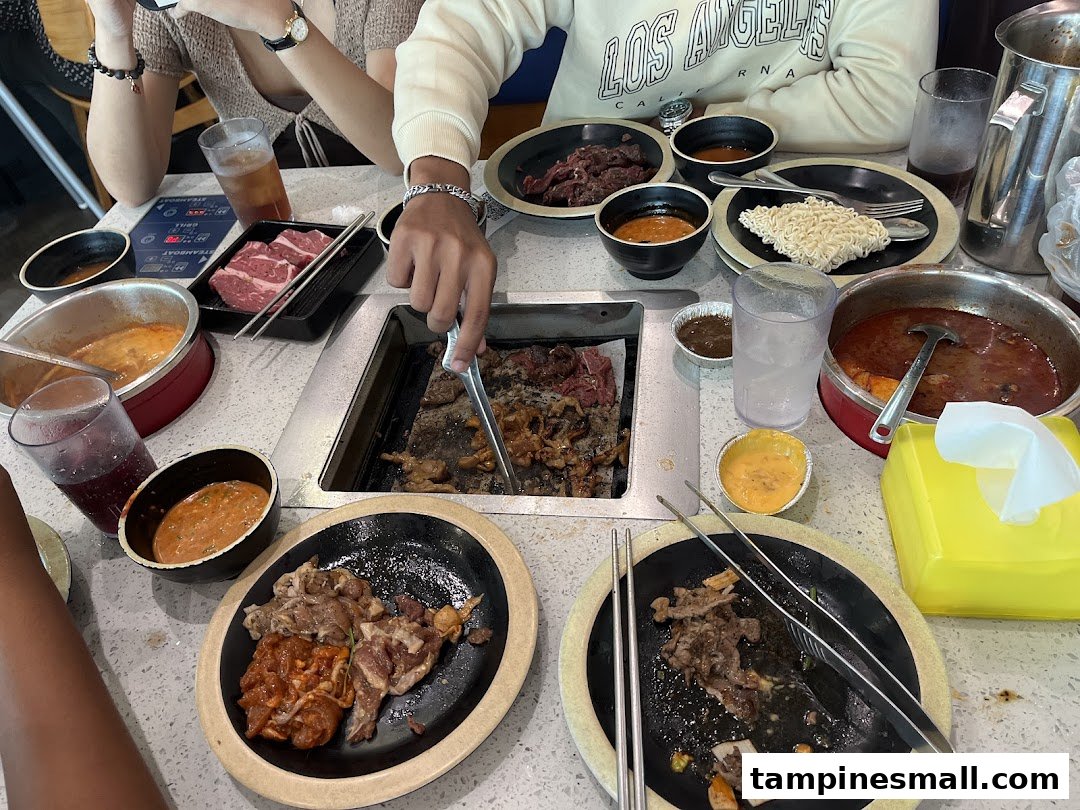 Diners enjoying a Korean BBQ and hotpot buffet with various meats and sauces at Seoul Garden.