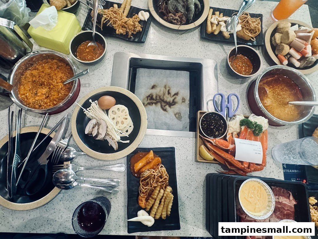 A table filled with a variety of hotpot and grill ingredients, cooked food, and sauces at Seoul Garden.