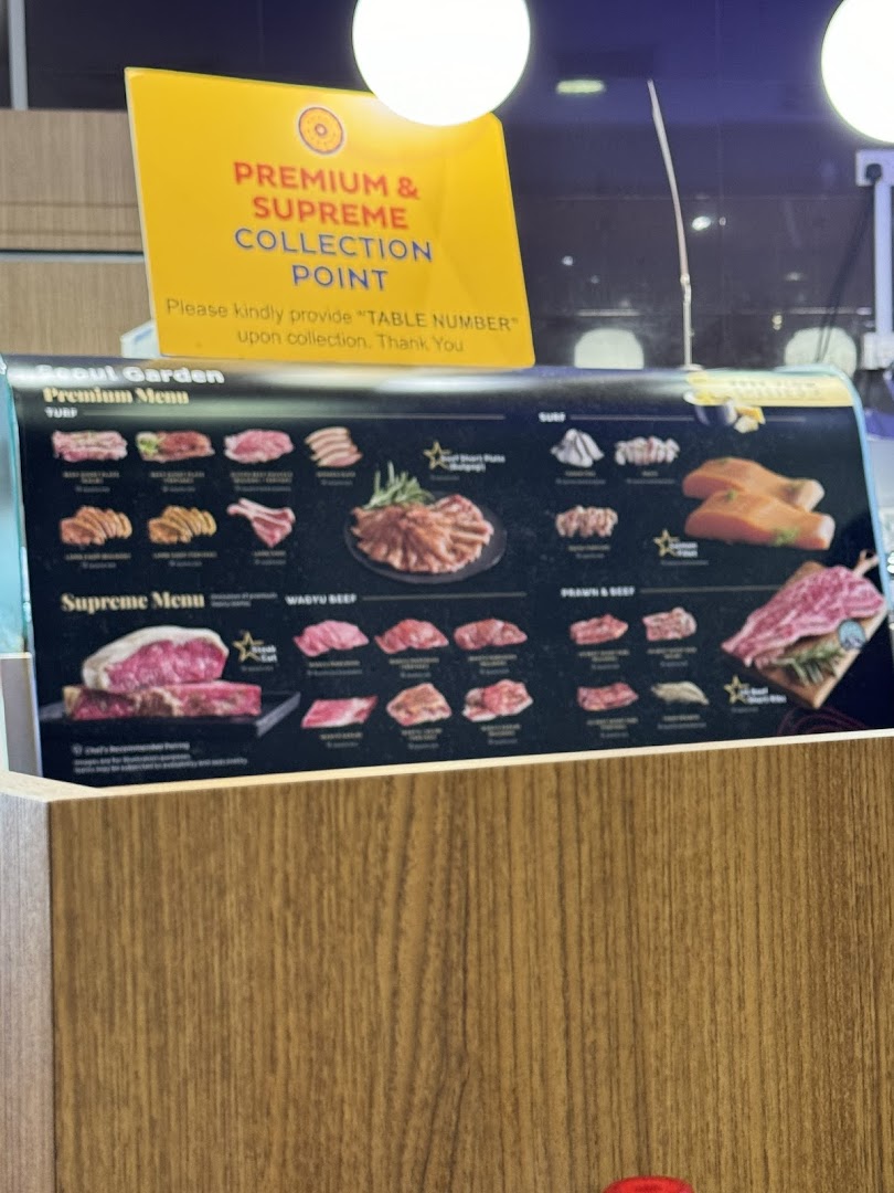 A menu board displaying premium and supreme meat cuts for a Korean BBQ restaurant, with a collection point sign.
