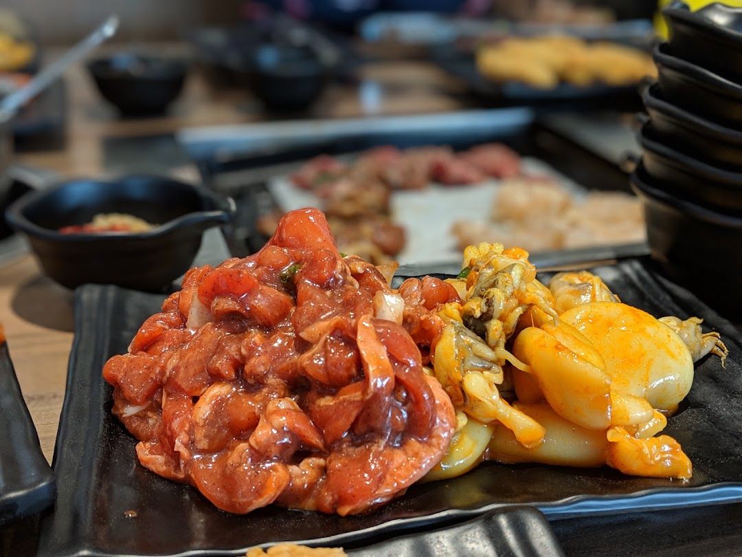 Close-up of marinated meat and seafood on black plates, ready for a hotpot or BBQ meal.